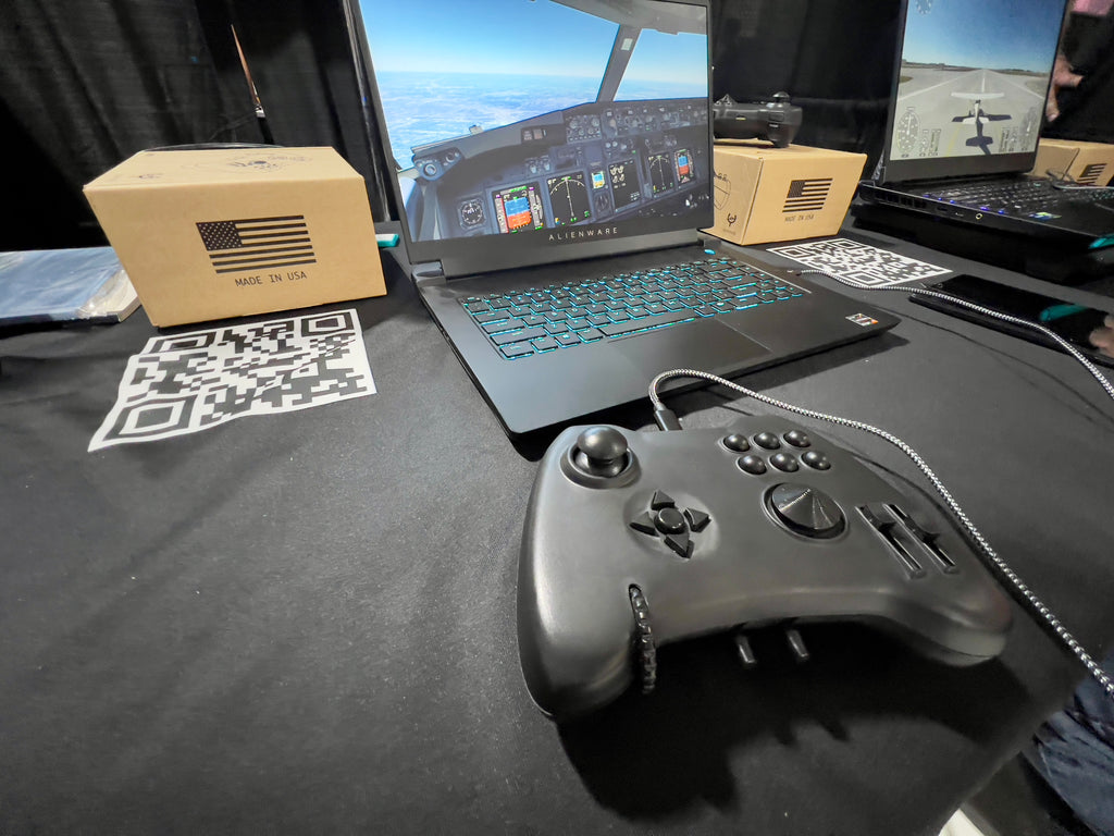 A black Yawman Arrow controller sits on a desk next to a gaming laptop.